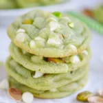 Soft and chewy pistachio pudding cookies with white chocolate chips and chopped pistachios, freshly baked on a cooling rack.